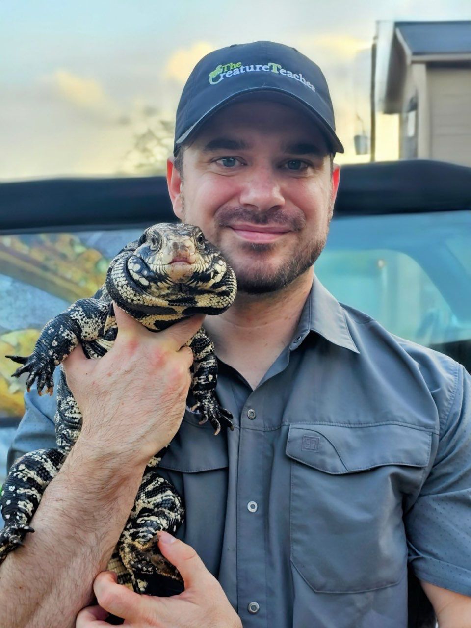 Rick, The Creature Teacher in Houston, holding a lizard in front of his car