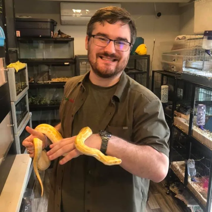 The Creature Teacher Colton smiling and holding a Burmese python