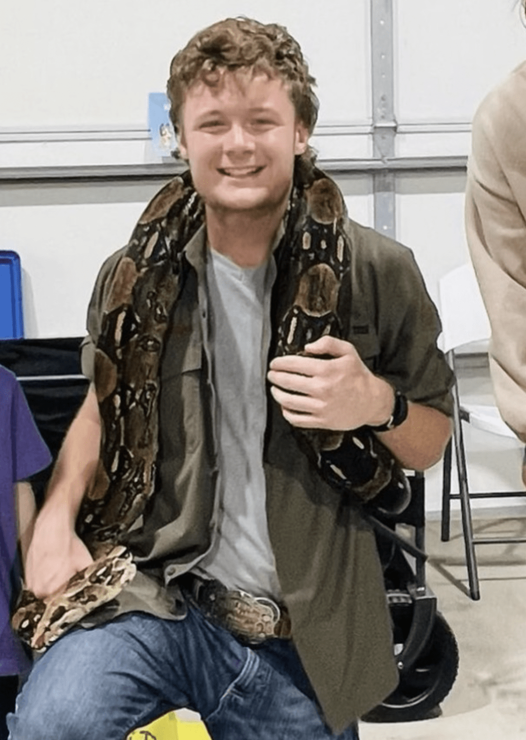 Instructor John holding a red tailed boa at a live animal birthday party