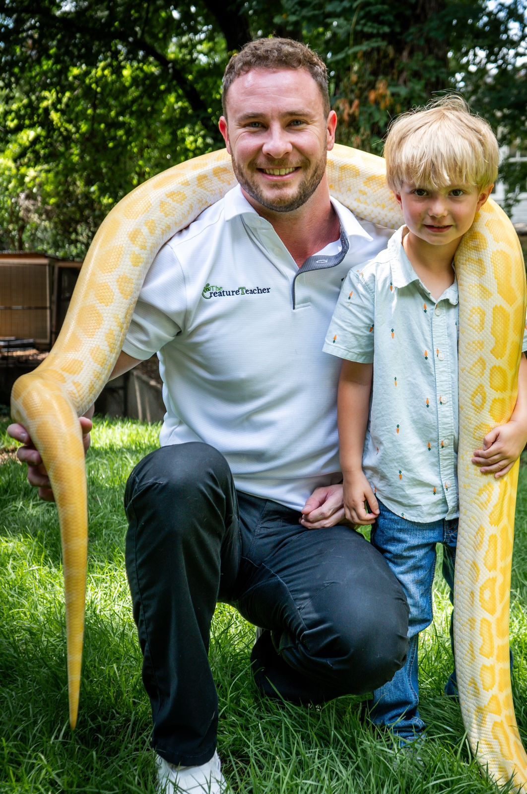 The Creature Teacher Kaleb smiling and holding a Burmese python at a child's birthday party