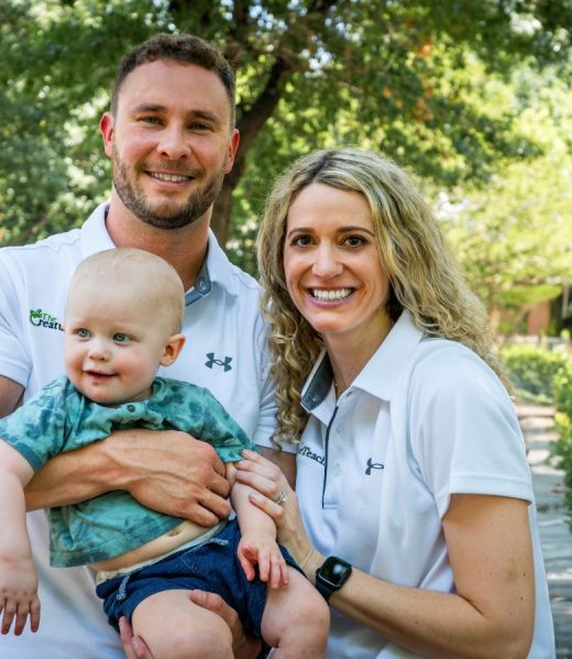 An instructor and his wife and child stand together to pose for a picture.